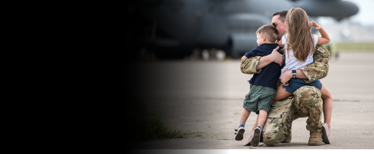 A photograph of an airman in uniform, hugging his young son and daughter