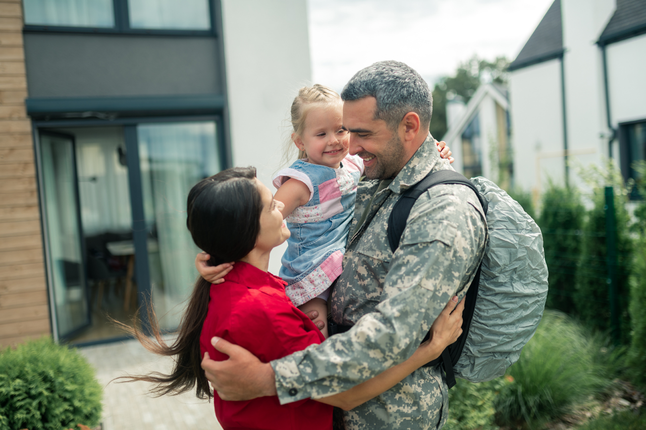 Soldier arriving home from a deployment hugging his daughter and wife
